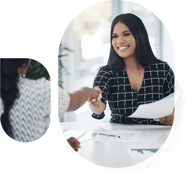 A woman sitting at a table with papers and a person holding her hand out.