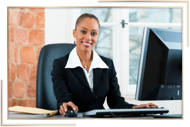 A woman sitting at her computer desk in front of a window.